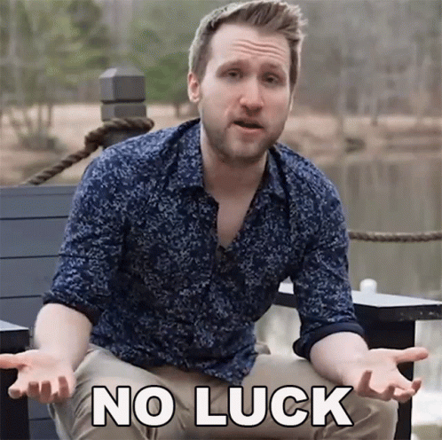 A Man In A Blue Shirt Says No Luck In Front Of A Lake GIF