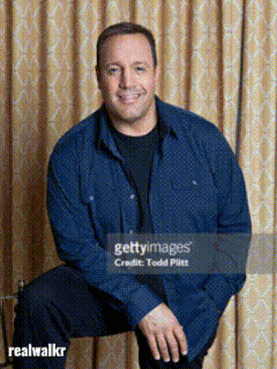 A Man In A Blue Shirt Sits In Front Of A Curtain GIF