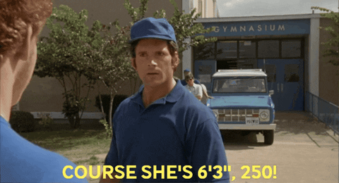 A Man In A Blue Shirt Stands In Front Of A Gymnasium GIF