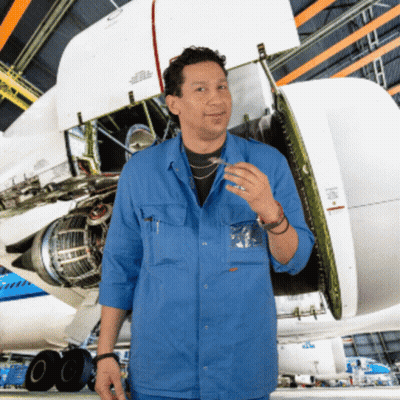 A Man In A Blue Shirt Stands In Front Of A Plane With The Wing Open GIF