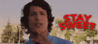 A Man In A Blue Shirt Stands In Front Of A Sign That Says Stay Sweet GIF