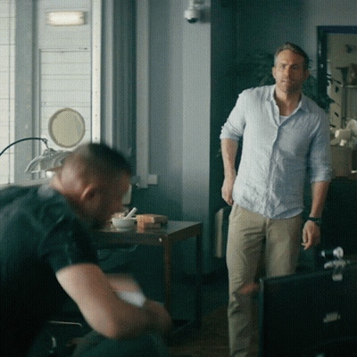 A Man In A Blue Shirt Stands Next To Another Man In Khaki Pants GIF