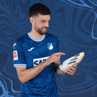 A Man In A Blue Shirt That Says Sap Holds A Soccer Shoe GIF