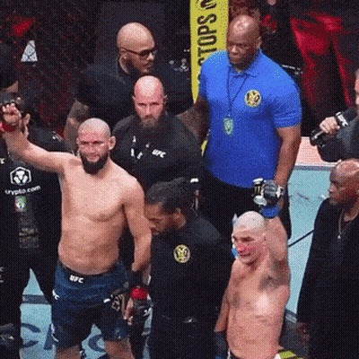 A Man In A Blue Shirt That Says Ufc Stands In Front Of A Group Of Men GIF
