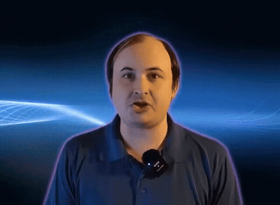 A Man In A Blue Shirt With A Microphone Around His Neck GIF