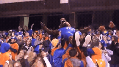 A Man In A Blue Shirt With The Letter T On It Is Being Lifted In The Air By A Crowd GIF