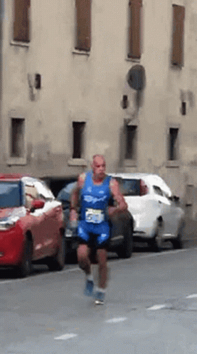 A Man In A Blue Shirt With The Number 55 On It Is Running Down The Street GIF