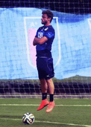 A Man In A Blue Shirt With The Word Fifa On It Stands On A Soccer Field GIF