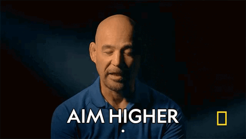 A Man In A Blue Shirt With The Words Aim Higher Above Him GIF