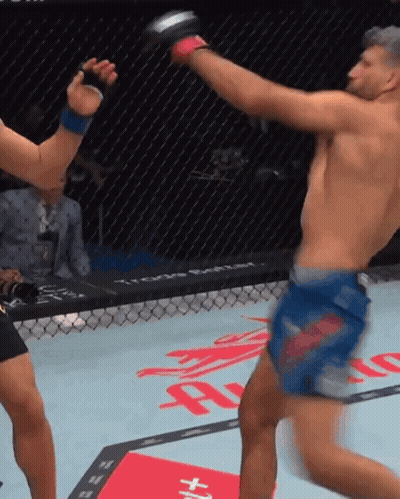 A Man In A Blue Shorts Kicks Another Man In A Cage GIF