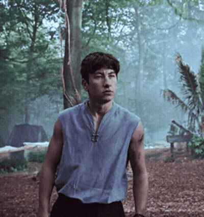 A Man In A Blue Sleeveless Shirt Is Standing In The Woods GIF