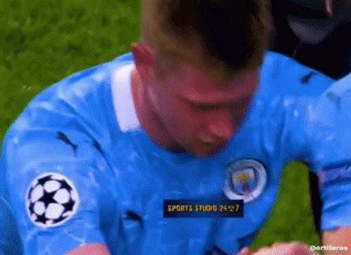 A Man In A Blue Soccer Jersey Is Kneeling On The Field . GIF