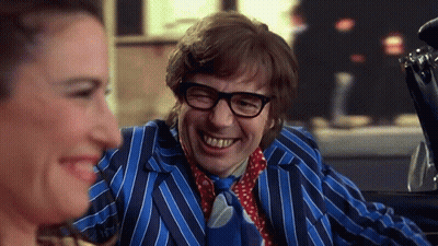 A Man In A Blue Striped Suit And Tie Is Laughing While A Woman Looks On . GIF