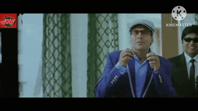 A Man In A Blue Suit Adjusts His Tie In Front Of A Screen That Says Kinemaster GIF