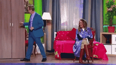 A Man In A Blue Suit And A Woman In A Blue Robe Are Dancing In A Room GIF