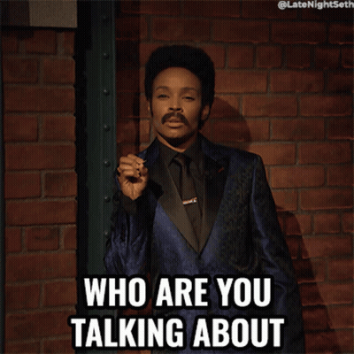 A Man In A Blue Suit And Black Tie Is Holding A Cigarette And Says Who Are You Talking About GIF