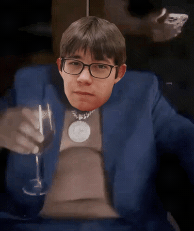 A Man In A Blue Suit And Glasses Is Holding A Wine Glass GIF