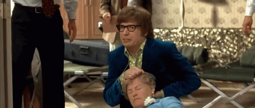 A Man In A Blue Suit And Glasses Is Putting His Hand On A Woman 'S Head GIF