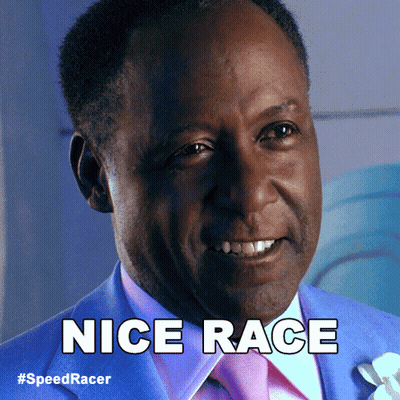 A Man In A Blue Suit And Pink Tie Is Smiling And Says Nice Race GIF