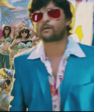 A Man In A Blue Suit And Red Sunglasses Is Standing In Front Of A Crowd GIF