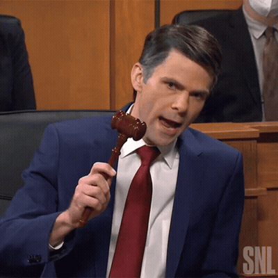 A Man In A Blue Suit And Red Tie Is Holding A Wooden Gavel With Snl Written On It GIF
