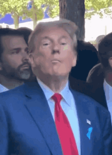 A Man In A Blue Suit And Red Tie Is Making A Face GIF