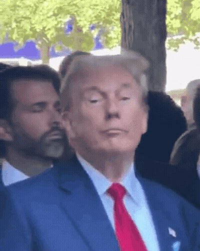 A Man In A Blue Suit And Red Tie Stands In Front Of A Crowd GIF