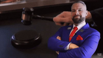 A Man In A Blue Suit And Red Tie Stands In Front Of A Judge 'S Gavel With The Number 113 On It GIF
