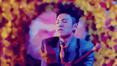 A Man In A Blue Suit And Tie Is Playing A Guitar GIF