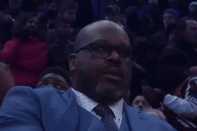 A Man In A Blue Suit And Tie Is Sitting In A Crowd Watching A Basketball Game GIF
