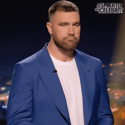 A Man In A Blue Suit And White Shirt Is Standing In Front Of A Sign That Says " Are You Smarter Than Celebrity " GIF