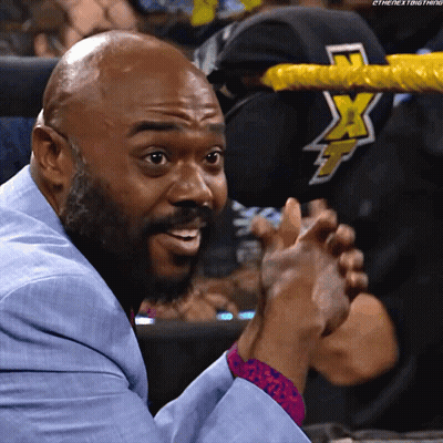 A Man In A Blue Suit Is Clapping In Front Of A Wrestling Ring With The Letters X On It GIF