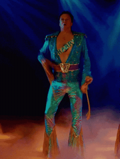 A Man In A Blue Suit Is Dancing In A Dark Room GIF