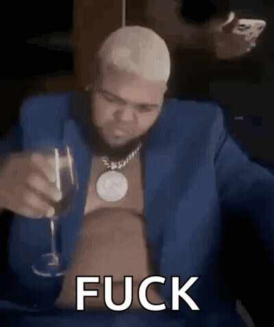 A Man In A Blue Suit Is Holding A Glass Of Wine And Smoking A Cigarette . GIF