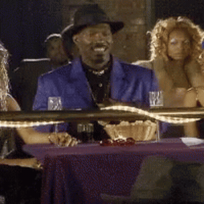A Man In A Blue Suit Is Sitting At A Table GIF