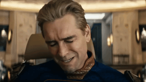 A Man In A Blue Suit Is Sitting In A Chair With His Eyes Closed And His Mouth Open . GIF