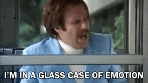 A Man In A Blue Suit Is Sitting In Front Of A Window With His Mouth Open . GIF