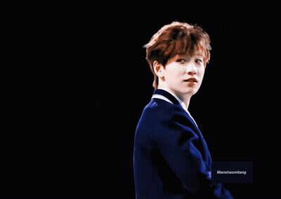 A Man In A Blue Suit Is Smiling In Front Of A Black Background With Marshhaomliang Written On It GIF