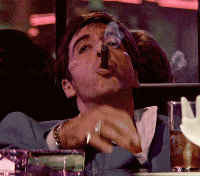 A Man In A Blue Suit Is Smoking A Cigar With Smoke Coming Out Of His Mouth GIF