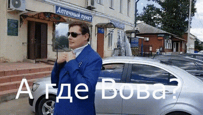 A Man In A Blue Suit Is Standing In Front Of A Building That Says " Аптечный Пункт " On It GIF