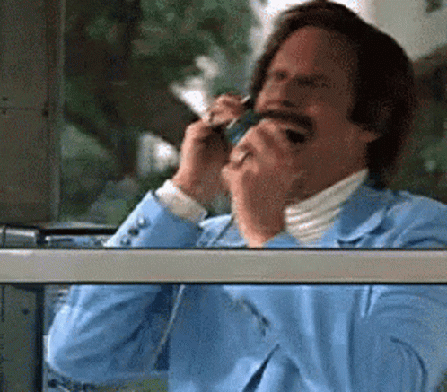 A Man In A Blue Suit Is Talking On A Cellphone GIF
