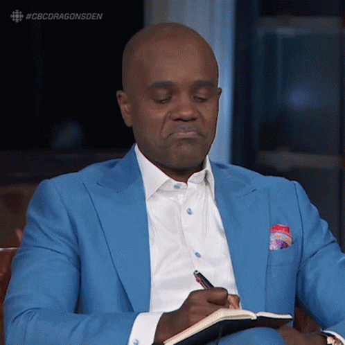 A Man In A Blue Suit Is Writing In A Book GIF