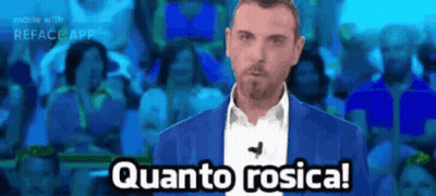 A Man In A Blue Suit Says Quanto Rosica In Front Of A Crowd Of People GIF