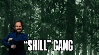 A Man In A Blue Suit Says " Shill Gang " In Front Of A Forest GIF