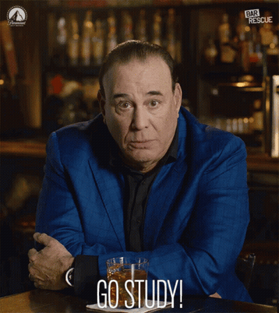 A Man In A Blue Suit Sits At A Table With A Glass Of Whiskey And The Words Go Study Below Him GIF