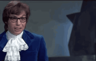 A Man In A Blue Suit Stands In Front Of A Green Sign That Says Gp GIF