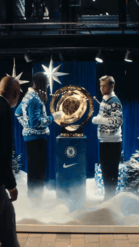 A Man In A Blue Sweater Holds A Trophy With The Chelsea Logo On It GIF