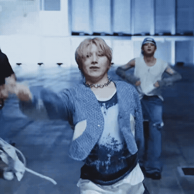 A Man In A Blue Sweater Is Dancing In A Room . GIF