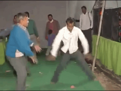 A Man In A Blue Sweater Is Dancing With Another Man In A White Shirt GIF
