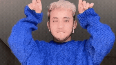 A Man In A Blue Sweater Is Giving A Thumbs Up Sign GIF